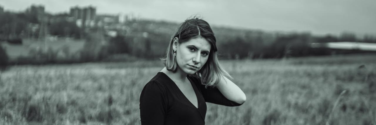 What to Know If You Have No Boundaries With Your Family black and white photo of woman standing in field looking into camera with sadness