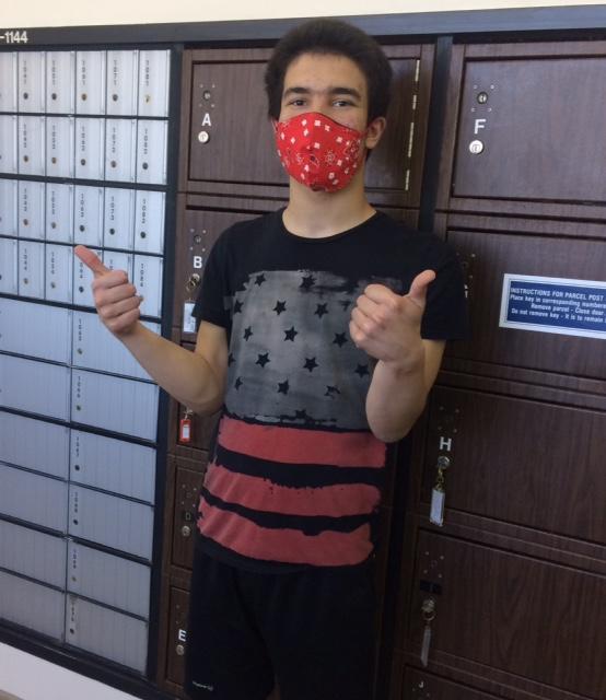 a teenager wearing a red mask at the post office giving a thumbs up