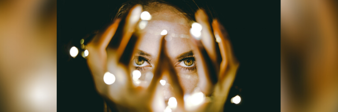 Woman holding string lights in front of her face