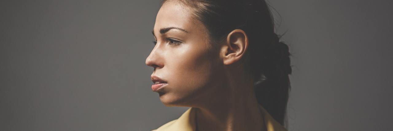 What It's Really Like to Hear Voices With Bipolar Disorder photo of woman looking right against gray background