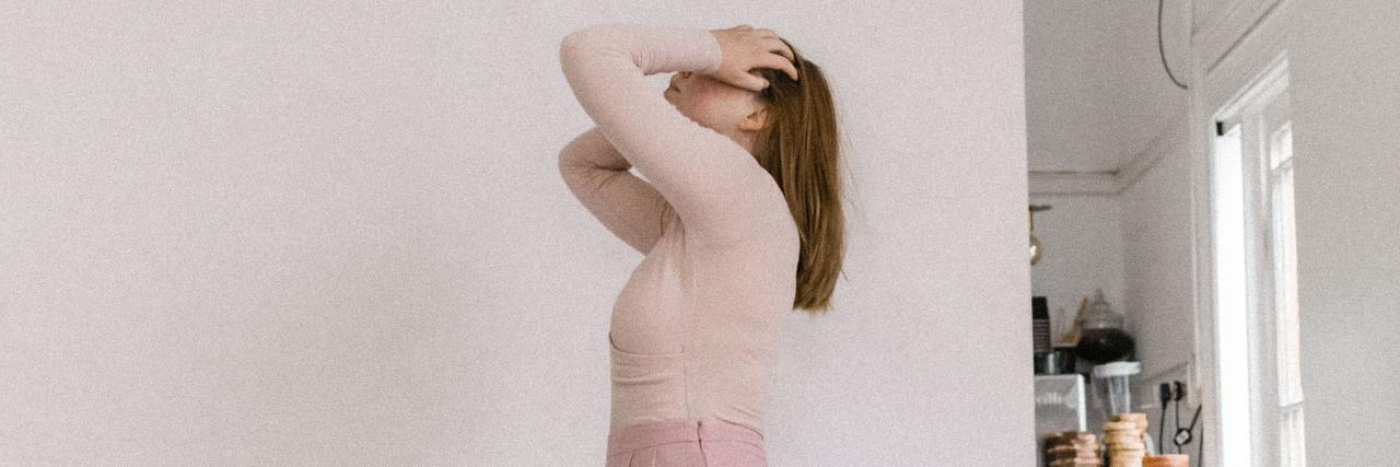 What's the Difference and Similarities Between Anxiety and Mania? photo of woman with her hands on her head, face hidden, looking stressed