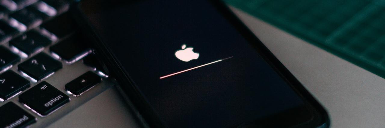 Apple’s iOS14 Includes New Accessibility Features for Disabled Users iPhone updating software plugged into a laptop computer