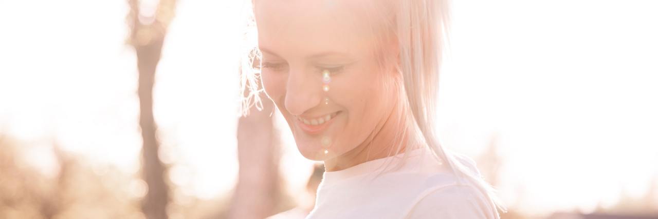 Being Friends With Someone With Mal de Debarquement Syndrome photo of woman in sunlight, smiling nearby tree