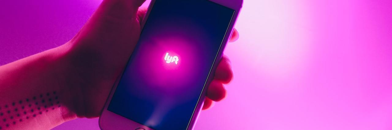 Hand holding a phone with the Lyft logo open on a purple background