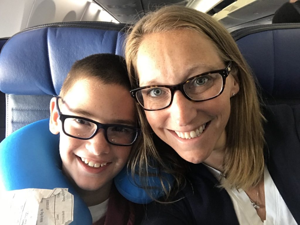 photo of contributor smiling and posing for the camera with her son while seated in airplane