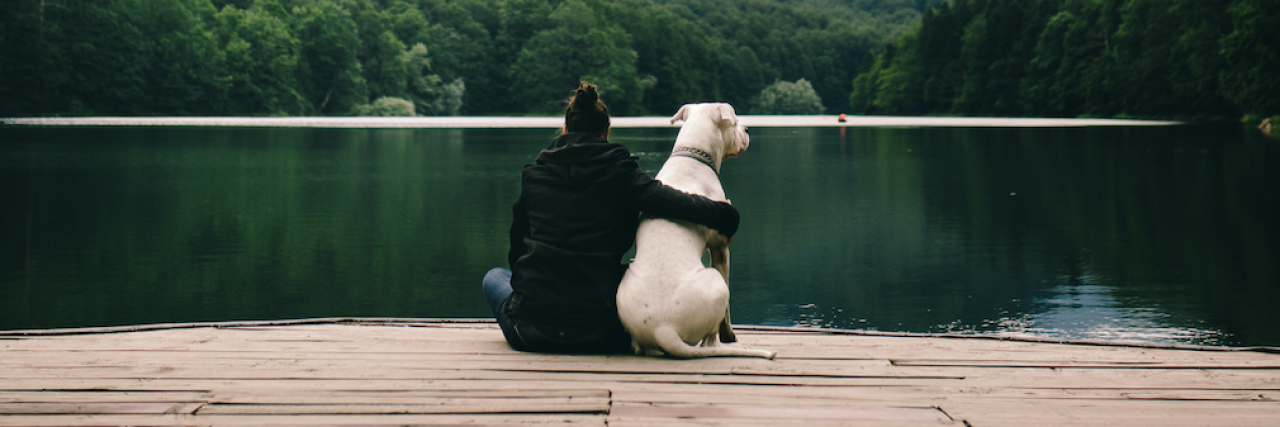 Woman sitting with a dog on dock at the lake