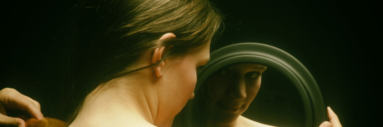 When I Feel Like My Chronic Illness Has Become My Identity Woman looking in mirror.