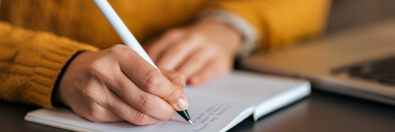 Why I Write as Someone on the Autism Spectrum Close up of woman writing in notebook.
