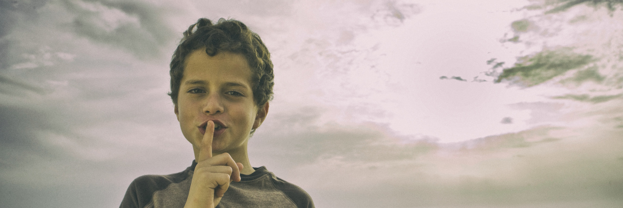 Kids With Disabilities Remain Invisible in the Educational System Young boy with finger to lips shushing.