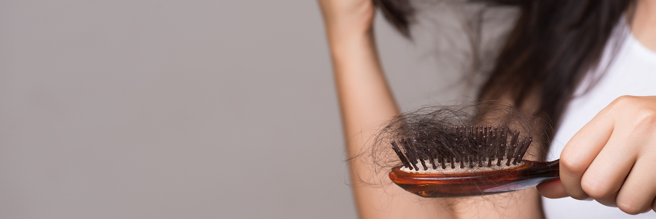 COVID-19 May Cause Hair Loss Woman with long brown hair holds a brush out to show hair loss