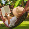 a woman is lying in a hammock reading a book