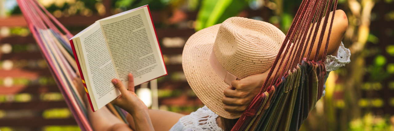 Staying Hopeful Amid Life With Severe Myalgic Encephalomyelitis a woman is lying in a hammock reading a book