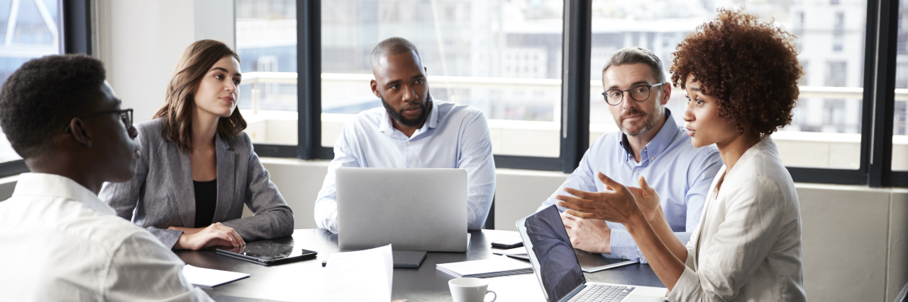 Why Supporting Autistic Employees Goes Beyond Hiring Initiatives Group of racially diverse coworkers at meeting.