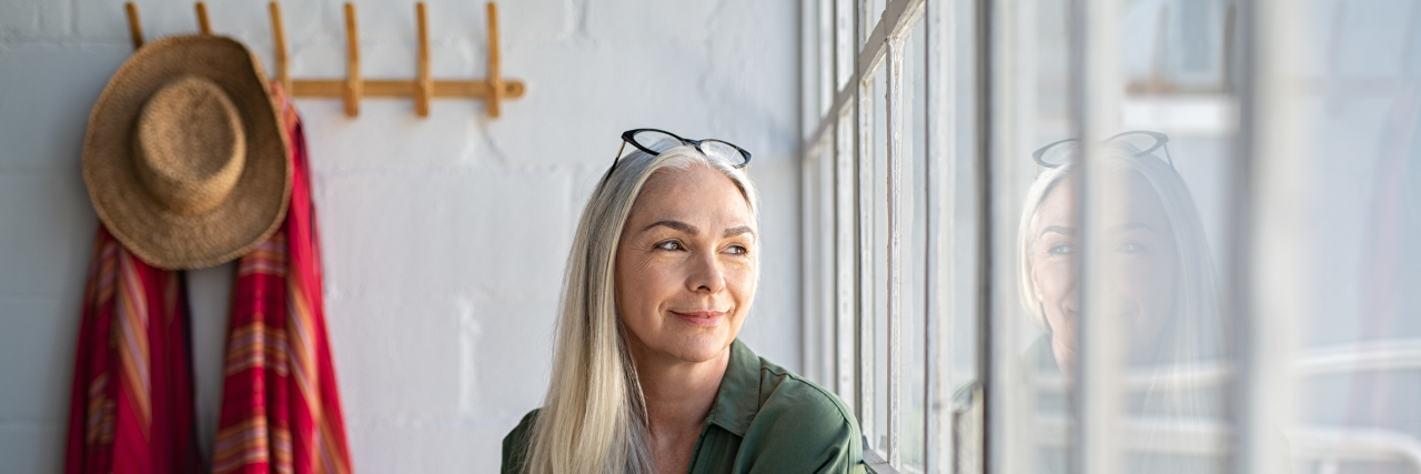10 Challenges People With Chronic Pain and Illness Often Face Smiling mature woman looking out window.