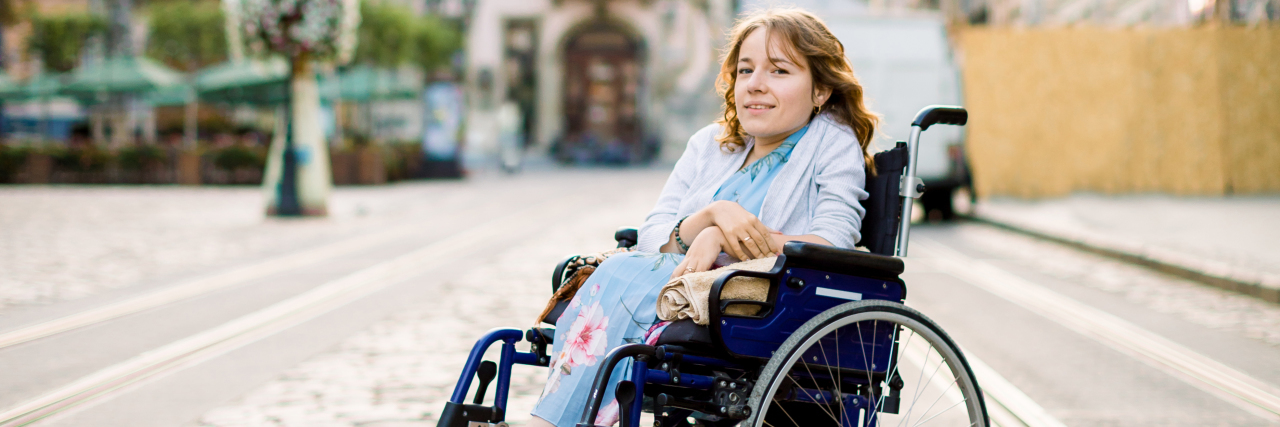 Please Don't Call Disability 'Sad' Disabled woman in wheelchair outdoors in plaza.