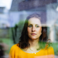 Young woman looks thoughtfully and sadly through the window