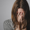 photo of woman crying with hands covering her face in clasped position