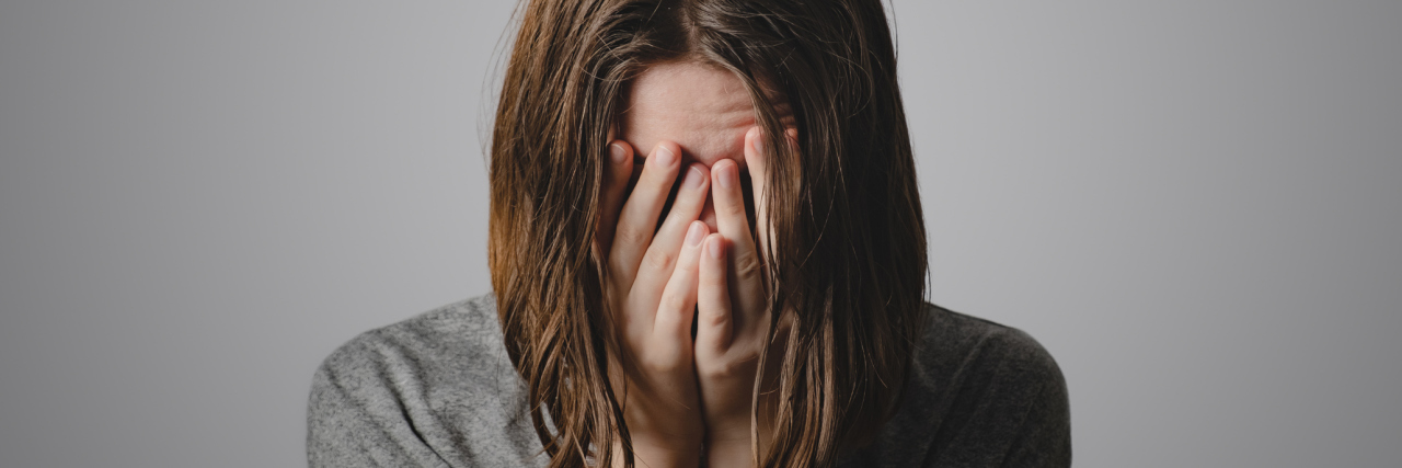 photo of woman crying with hands covering her face in clasped position