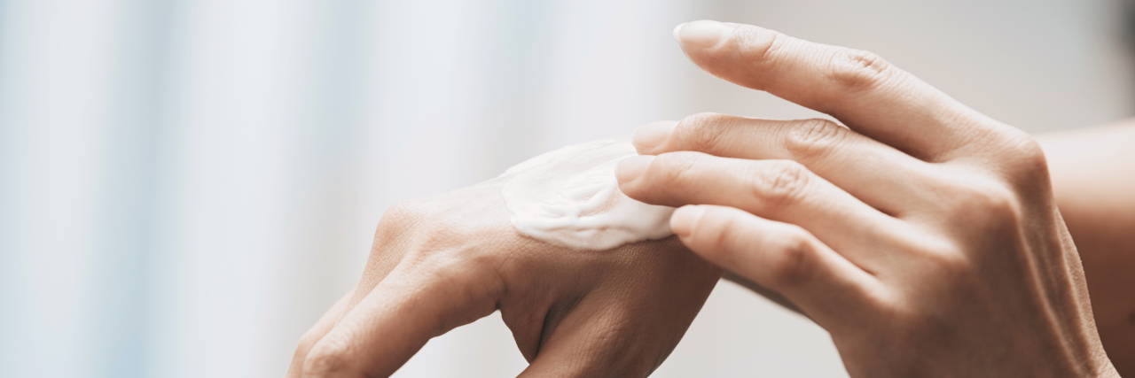 Woman applying moisturizing cream on hands.