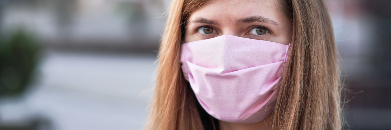 Communicating With a Speech Disorder While Wearing a Face Mask Young woman with pink hand made cotton face mask.