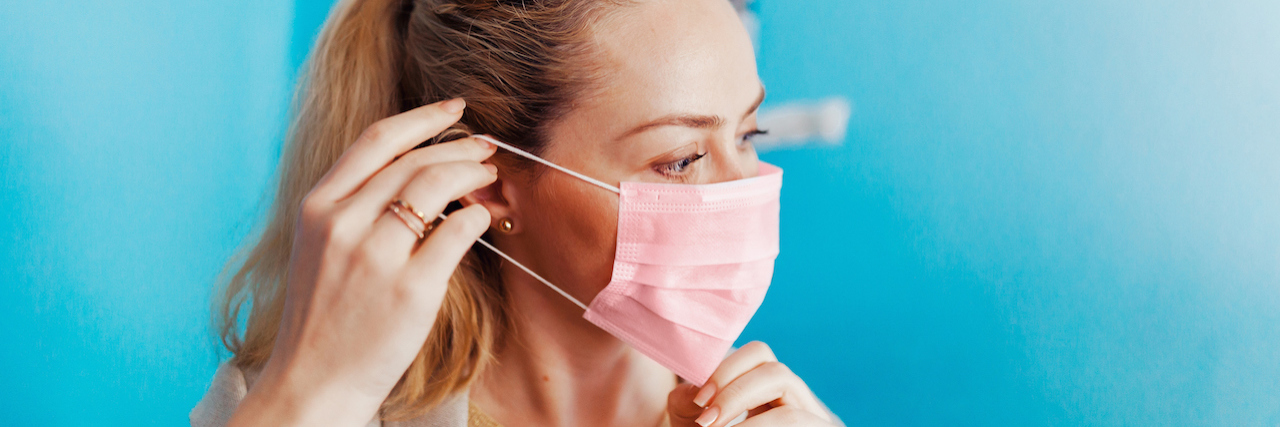 Mental Health Stigma Can Be a Risk Factor for COVID-19 Complications A woman putting on a mask