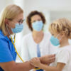 Doctor examining child in face mask.