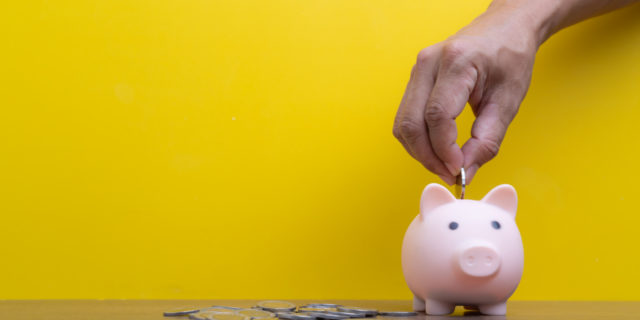 How Government Policy Makes People With Disabilities Live in Poverty Close-up hand putting coins in piggy bank.