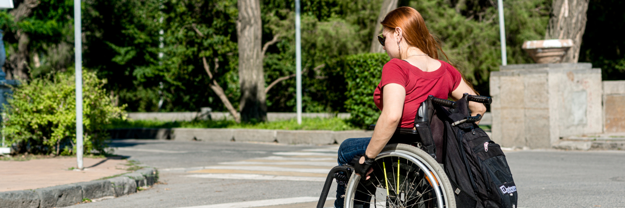 A young woman in a wheelchair at a pedestrian crossing.