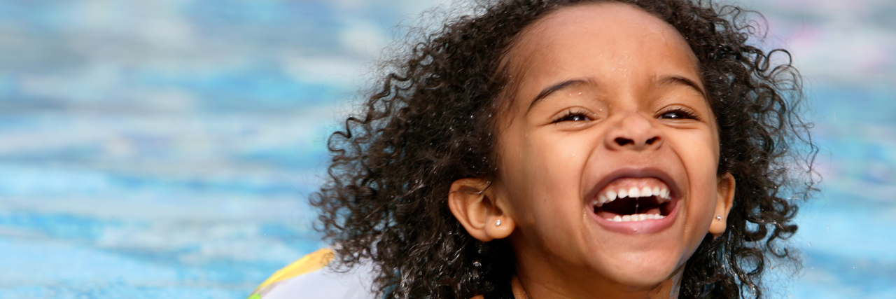 Children With Chronic Health Conditions and Summer Safety Happy young Black girl swimming in pool.