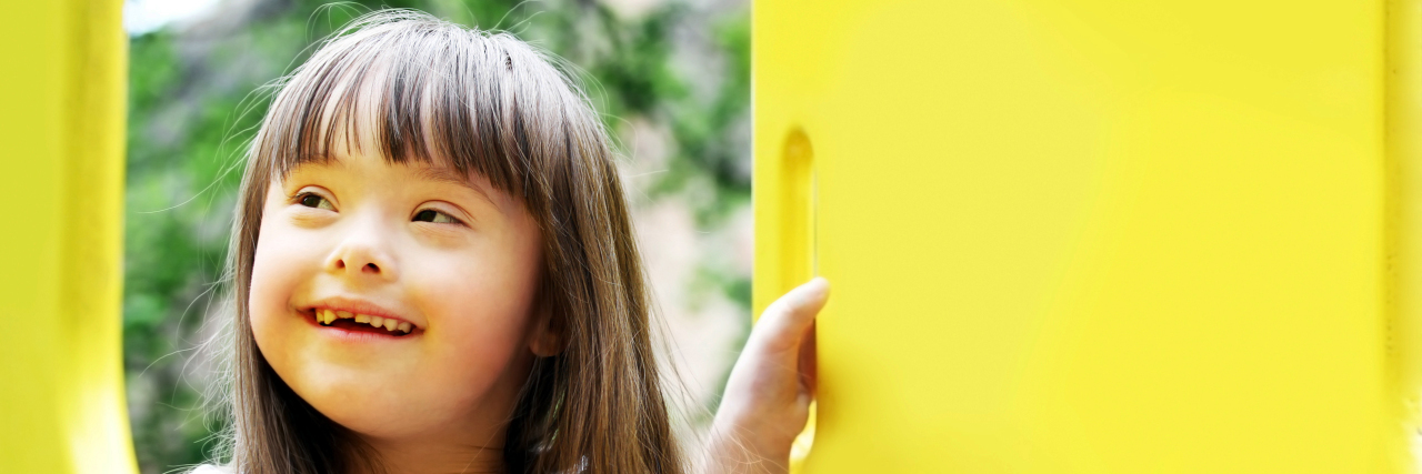 What Is Mosaic Down Syndrome? Portrait of young girl with Down syndrome on the playground