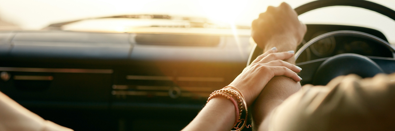 Sensory Overload and Brain Fog Make It Hard to Listen to Husband A woman holding her husband's hand in the car, his hands are on the wheel