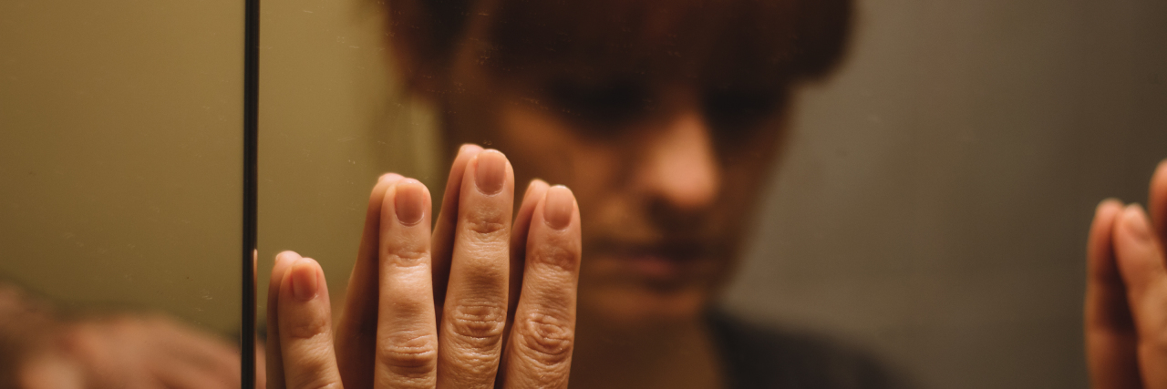 Sad woman looking in mirror.