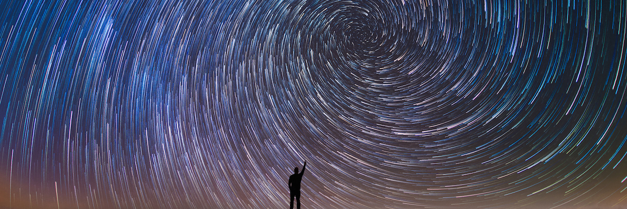 Silhouette of a man against a large spiral of stars