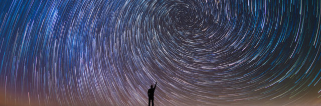 Silhouette of a man against a large spiral of stars