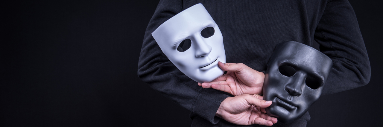 Why Do We Mask How We Cope as Autistic People? Man holding comedy and tragedy masks behind his back.