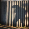 shadow of a boy with backpack against a ribbed concrete wall