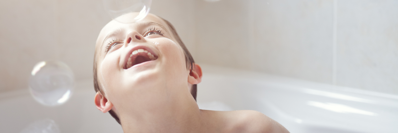 Learning to Communicate Better With My Son With Down Syndrome a boy is playing with bubbles in a bath