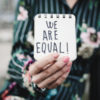 Woman shows notepad with the text "we are equal."