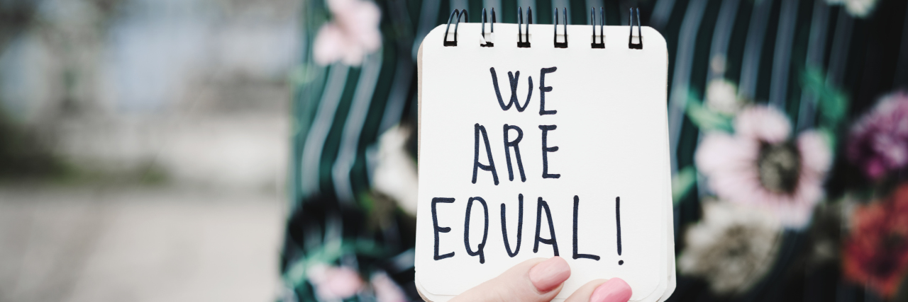 Celebrating Disability Pride Month During Turbulent 2020 Woman shows notepad with the text "we are equal."