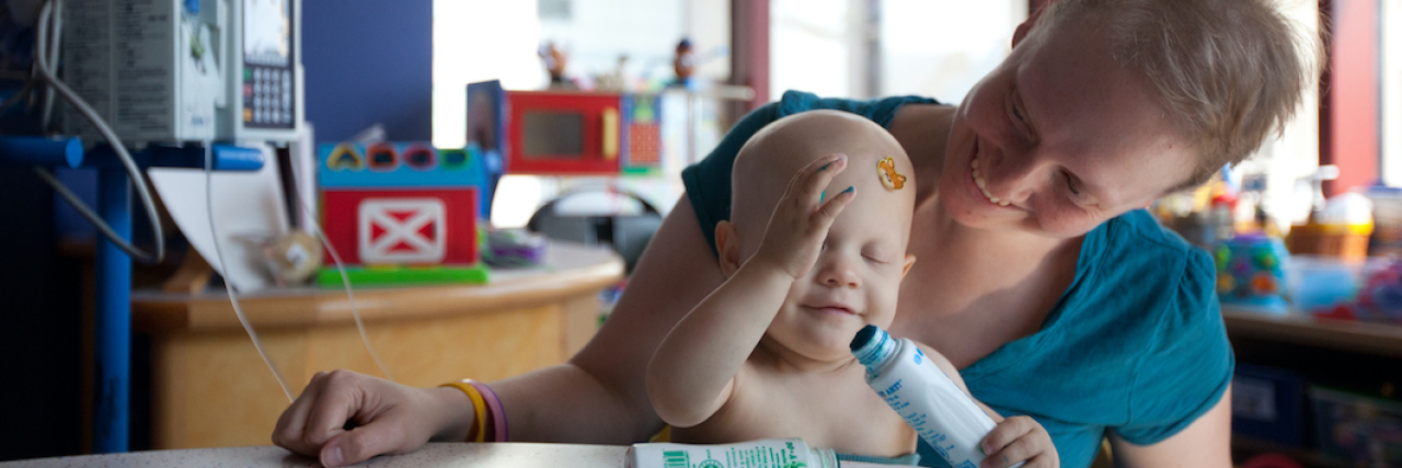 COVID-19: What Cancer Patients Know About 'New Normals' The author sitting in a hospital room with her daughter in her lap, drawing.