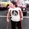 Woman wearing a white shirt with a wheelchair on it using crutches