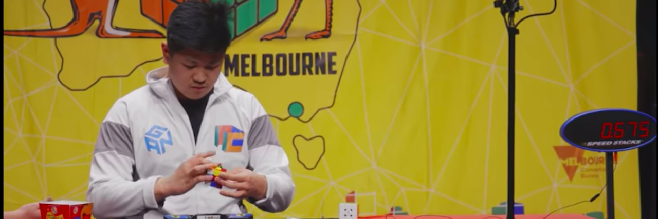 Autistic Teen Battles for Win in New Netflix Doc 'The Speed Cubers' Max Park, a teenager with dark hair, solves a Rubik's cube at a table