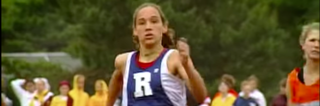 Female runner competing in a race, arms pumping, while wearing a blue and white jersey