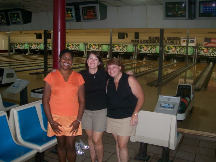 Alisa and her two friends smiling at a bowling ally
