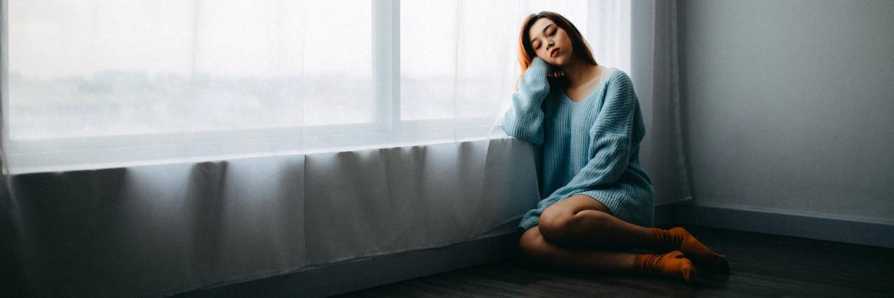 Self-Care for When You Feel Like You've Hit Rock Bottom photo of young woman sitting on floor beside a low window, resting her head on her hand