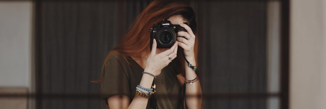 photo of woman taking a selfie in a mirror with the camera covering her face