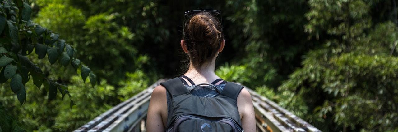 The Role Cultural Differences Play in Mental Health Treatment Woman wearing backpack crossing a metal walking bridge
