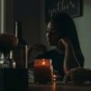 photo of Black woman sitting at a wooden counter, a candle nearby