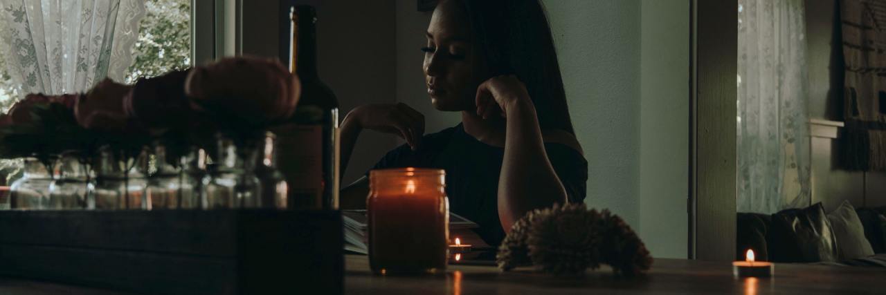 How to Have Healthy Relationships With Mental Illness photo of Black woman sitting at a wooden counter, a candle nearby
