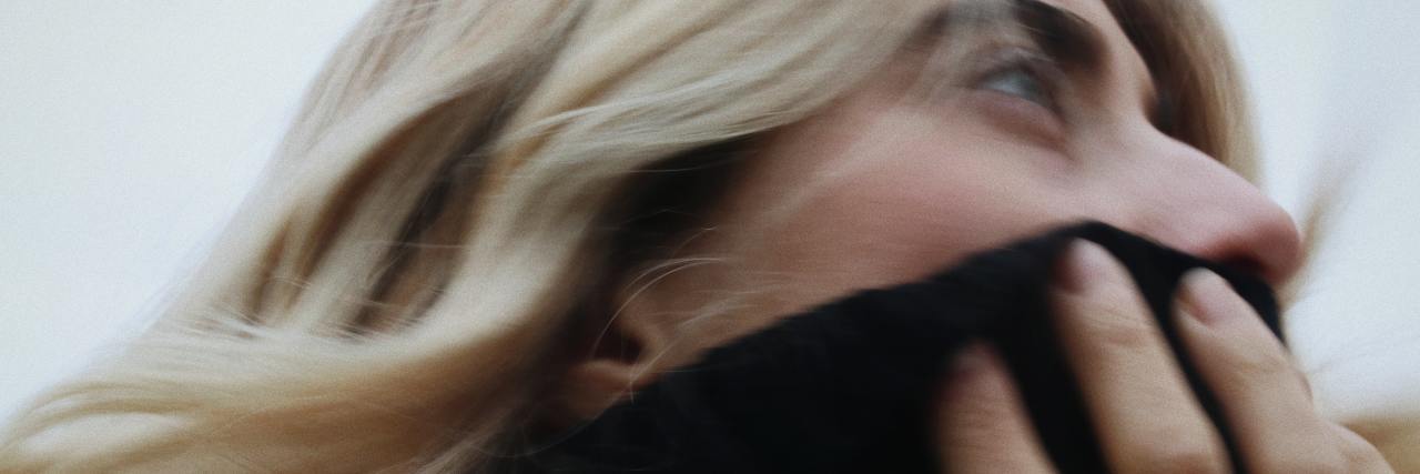 The Importance of Hope in Recovery from Mental Illness A woman looking to the side, covering her face with a dark sweater